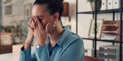 A woman sitting at a desk and looking stressed.