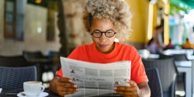 A woman reading a newspaper in a café.