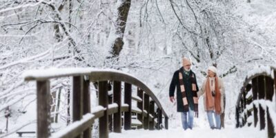 A couple walking across a bridge in the snow.