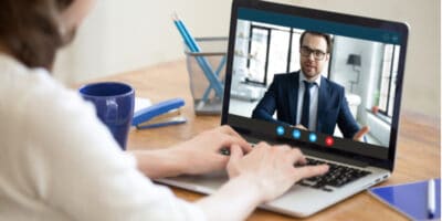A woman video conferencing on a laptop with a man.