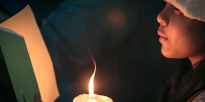 A child singing a Christmas carol by candlelight.