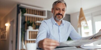 A man reading a newspaper at home.
