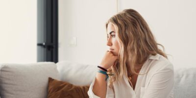 Woman sitting on a sofa, with an insecure expression on her face